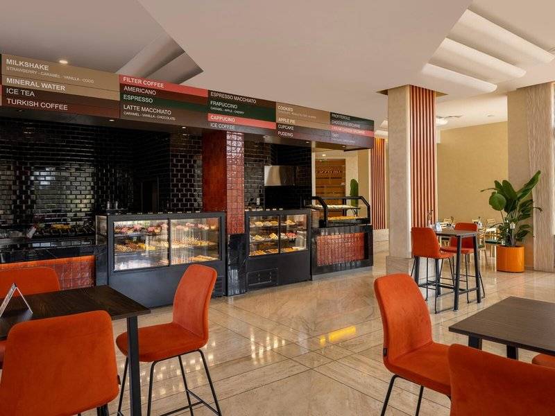 Innenansicht des Cafes im Megasaray Resort Side Hotel mit Speisen, Tischen und Stühlen.