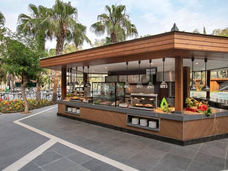 Außenbereich des Megasaray Resort Side Restaurants mit Essenstheken und Palmen im Hintergrund.