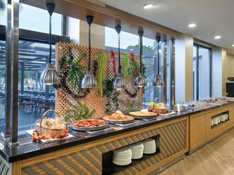 Buffet-Tisch im Megasaray Resort Side mit verschiedenen Speisen und Blick auf den Garten.