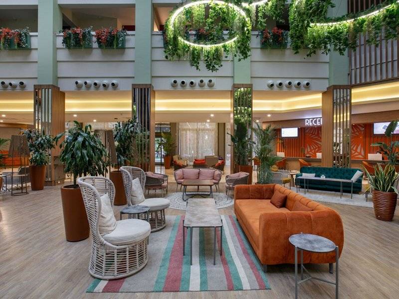 Lobby des Megasaray Resort Side Hotels mit Pflanzen, Sofas und Tischen.