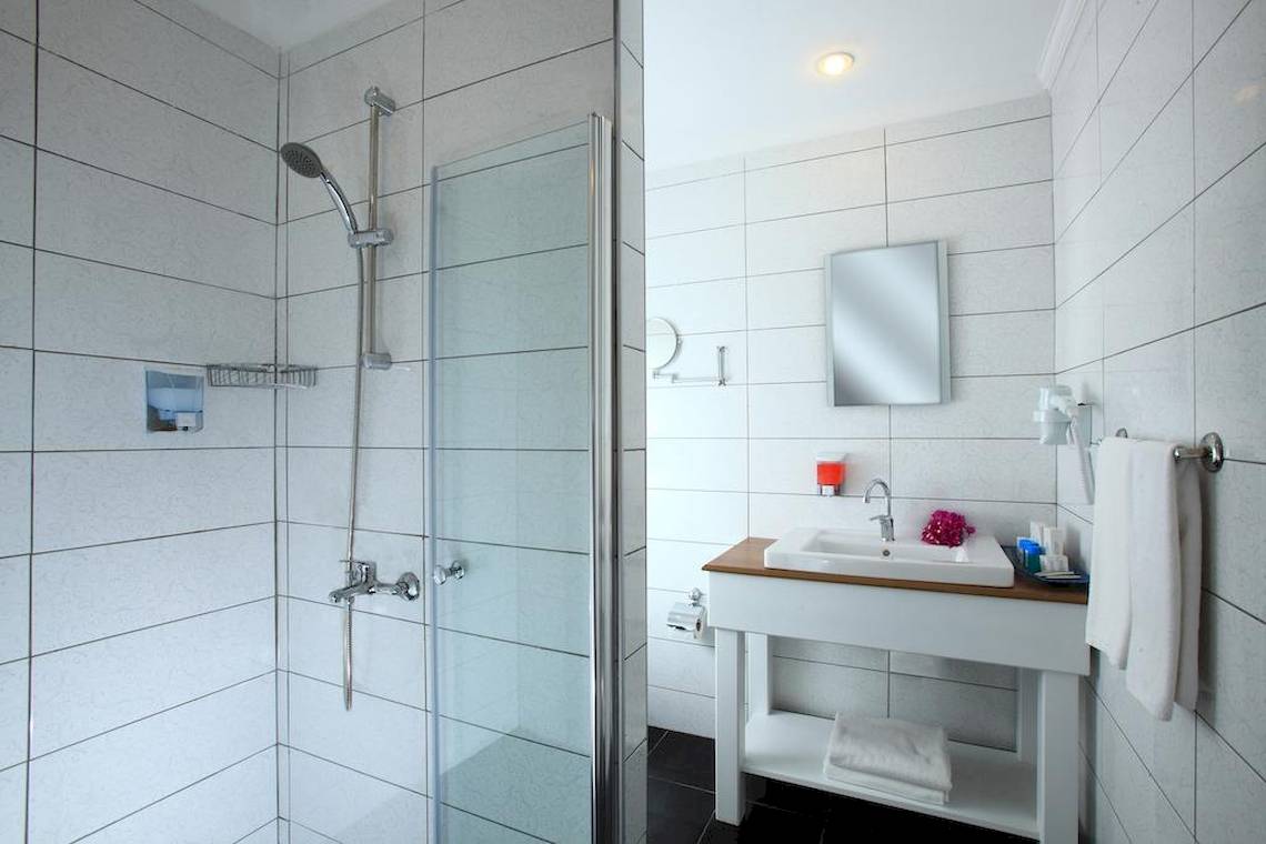 Das Badezimmer im Larissa Bodrum View Resort mit einer Glasdusche, einem Waschbecken und Handtüchern.