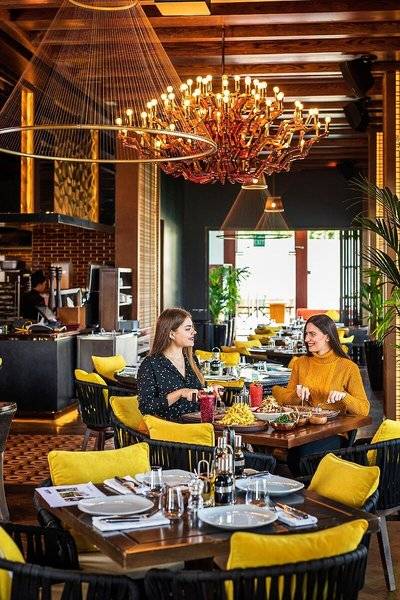 Im Sheraton Doha Resort Convention Hotel sitzen zwei Frauen am Tisch im Restaurant und essen.