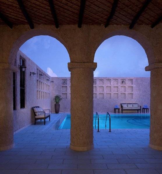 Innenpool im Souq Waqif Boutique Hotels mit gemauerten Säulen und einem Loungebereich.