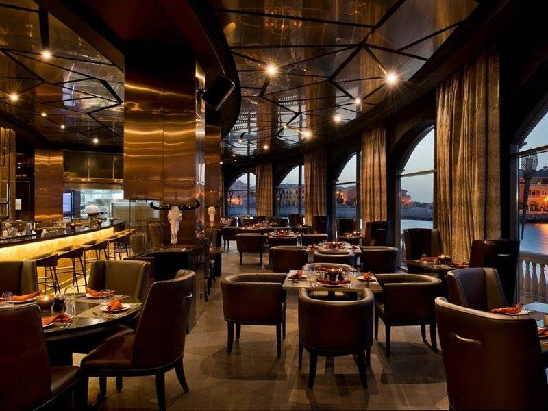 Innenansicht des Marsa Malaz Kempinski, The Pearl Restaurants mit runden Tischen und Stühlen.