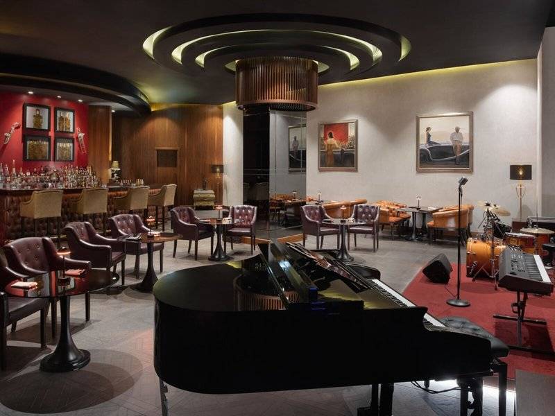 Loungebereich im Marsa Malaz Kempinski, The Pearl Hotel mit Klavier, Bar und gepolsterten Stühlen.