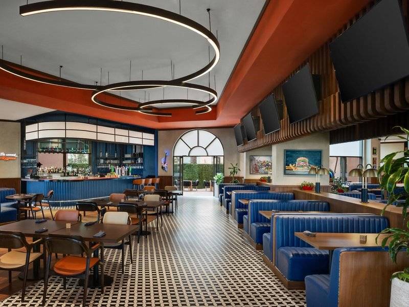 Innenansicht des Marsa Malaz Kempinski, The Pearl Restaurants mit blauen Bänken und Tischen, einer Theke und dekorativen Leuchten.