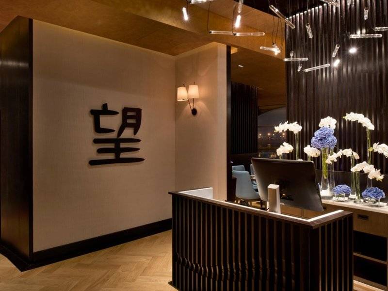Empfangsbereich des Marsa Malaz Kempinski mit chinesischem Zeichen an der Wand, Blumenarrangements und Schreibtisch.