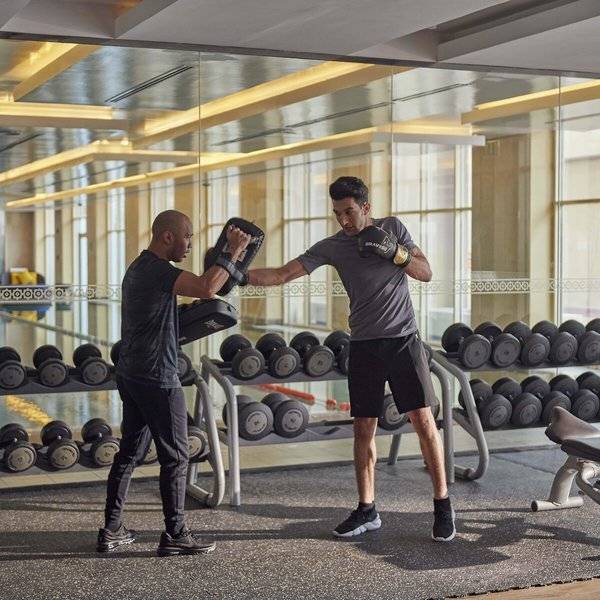Fitnesstraining im Grand Hyatt Doha Hotel & Villas mit zwei Männern, die Boxhandschuhe tragen.