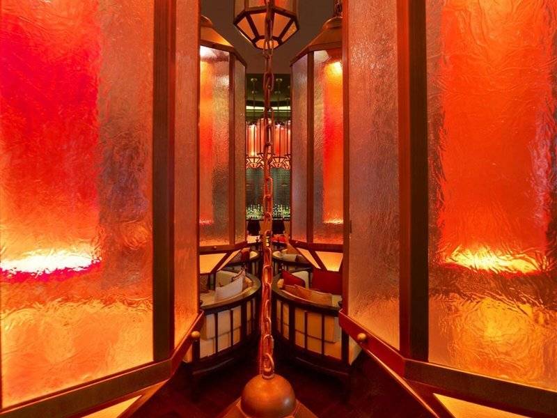 Inneneinrichtung des W Doha Hotel mit orange leuchtenden Trennwänden und Tischen.