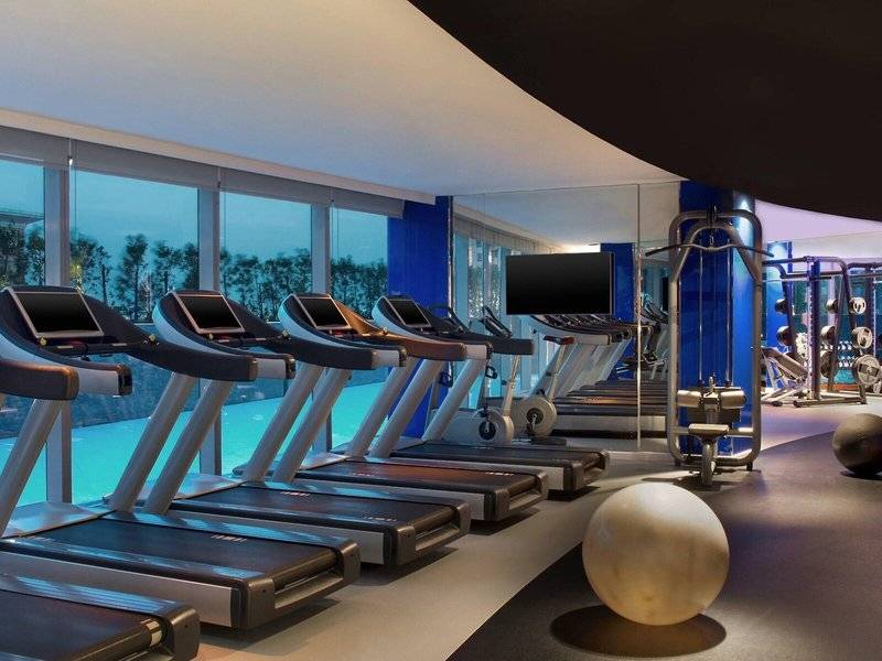 Fitnessstudio im W Doha Hotel & Residences mit mehreren Laufbändern und Trainingsgeräten.