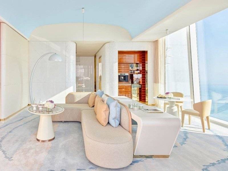 Wohnzimmer im Fairmont Doha mit Couch, Tisch, Stühlen und Blick auf den Ozean.