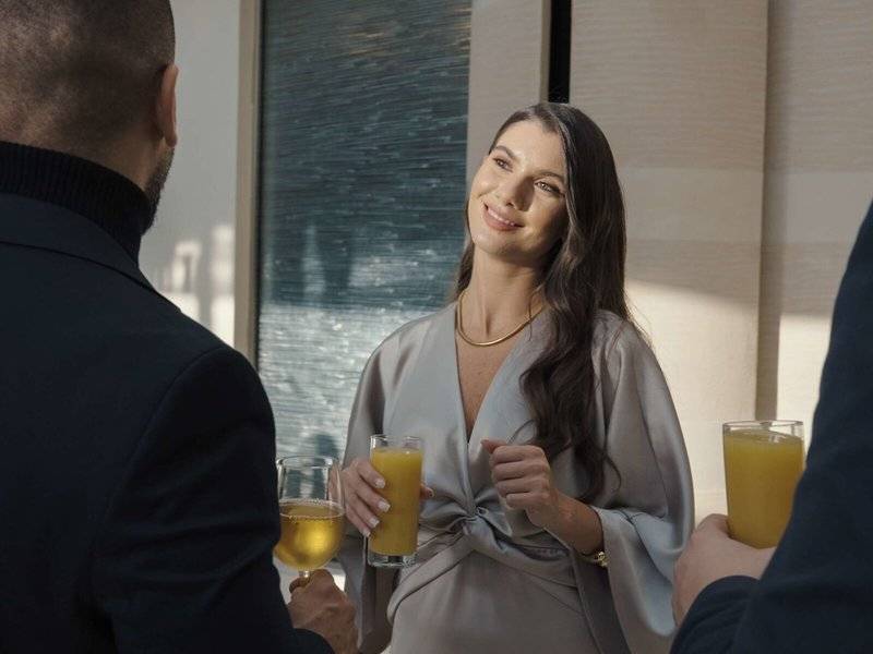 Frau im grauen Kleid trinkt Cocktail im Hyatt Regency Oryx Doha
