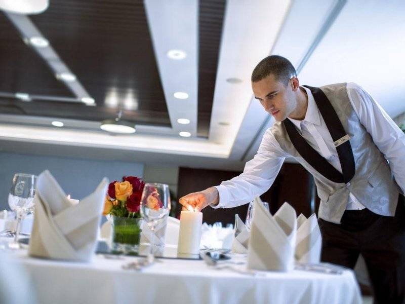 Kellner, der ein brennendes Kerze in einem eleganten Restaurant des Hyatt Regency Oryx Doha anzündet.