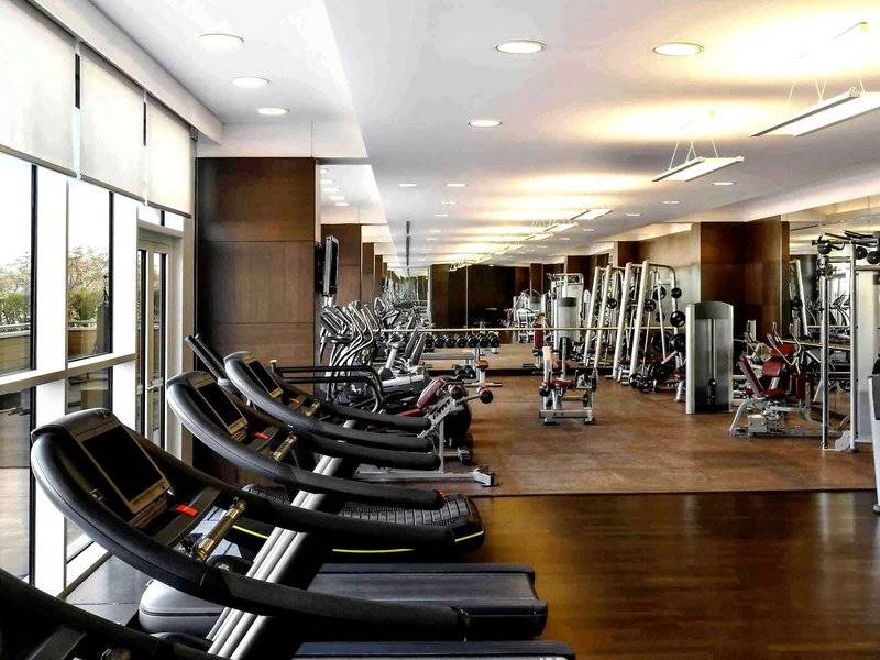 Fitnesscenter im Hyatt Regency Oryx Doha mit vielen Geräten und Geräten, die in einer Reihe aufgestellt sind.