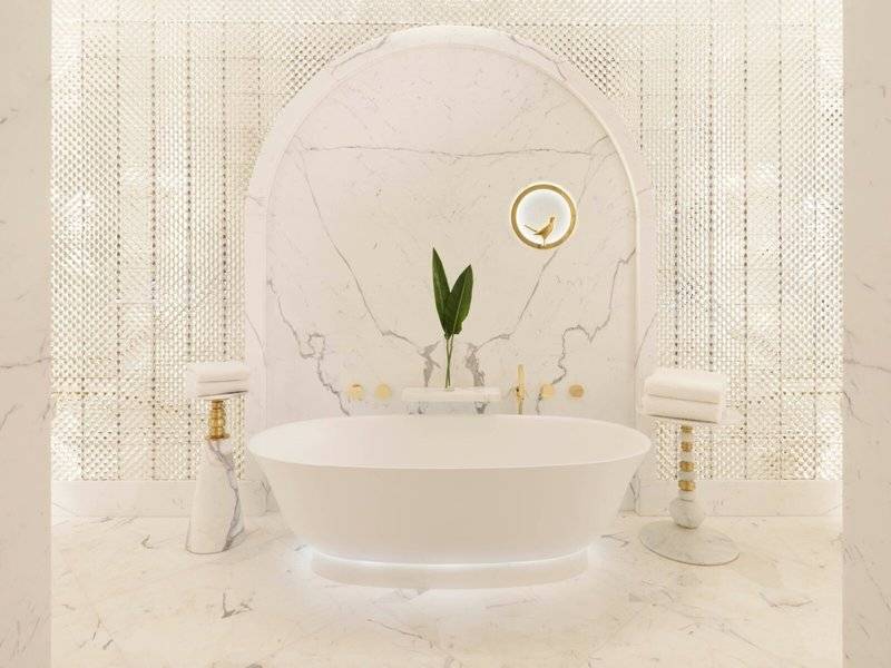 Ein Badezimmer im Raffles Doha Hotel mit einer weißen Badewanne und Marmorboden.