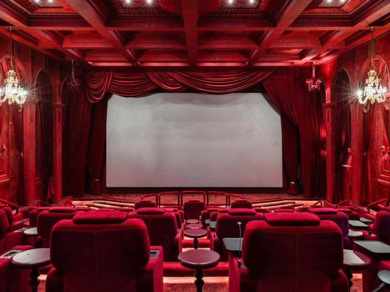Kinosaal im Raffles Doha mit roten Sitzen und Vorhängen, große Leinwand und Kronleuchter