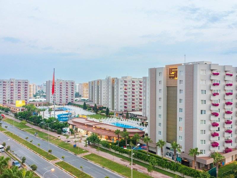 Außenansicht des Grand Park Lara Hotels mit mehreren Gebäuden, Swimmingpool und Flaggen.