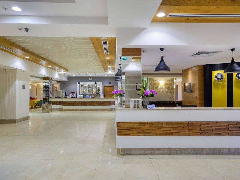 Reception des Grand Park Lara Hotels mit Blumenarrangements und moderner Einrichtung.