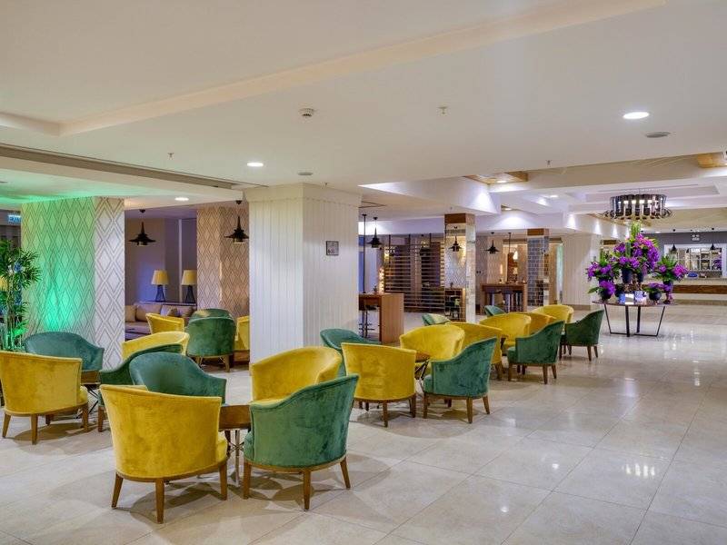 Lobby des Grand Park Lara Hotels mit farbenfrohen Sesseln und einem großen Blumenstrauß.