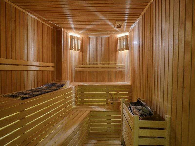 Innenansicht einer Holzsauna mit Liegeflächen, Holzeimer und Holzregale.