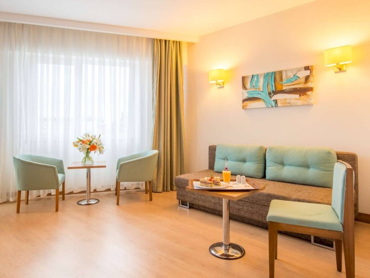 Wohnzimmer des Grand Park Lara Hotels mit Couch, Tisch und Stühlen.