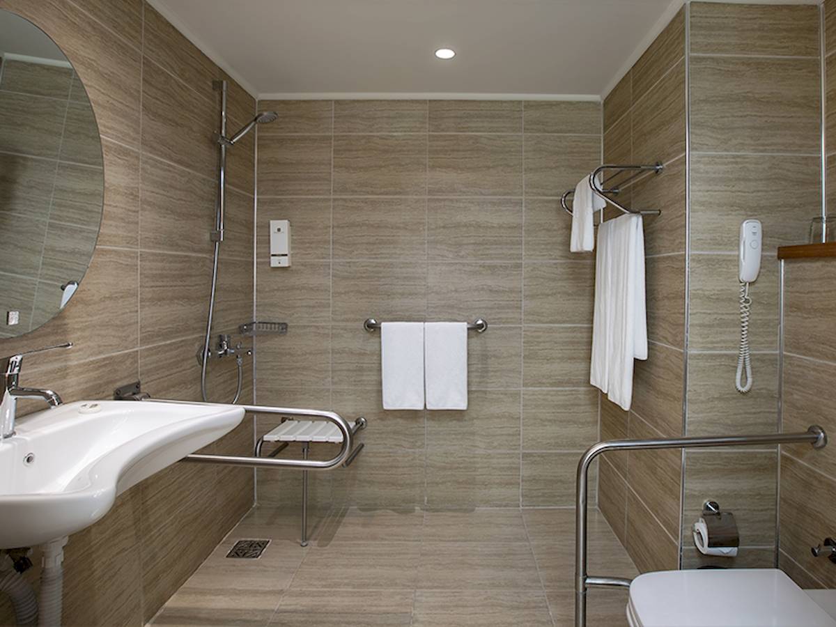 Behindertengerechtes Badezimmer im Grand Park Lara Hotel mit ebenerdiger Dusche, Handtuchhalter und barrierefreien Annehmlichkeiten.