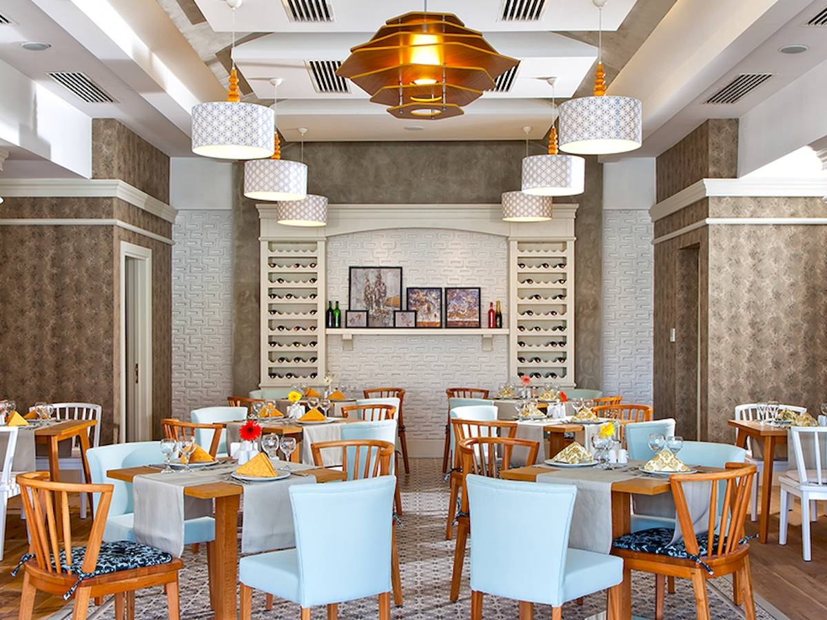 Innenbereich des Grand Park Lara Restaurants mit blauen Stühlen und gedeckten Tischen.