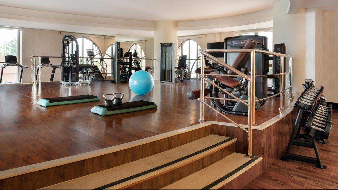 Fitnessraum im St. Regis Doha mit verschiedenen Trainingsgeräten und einem blauen Medizinball.