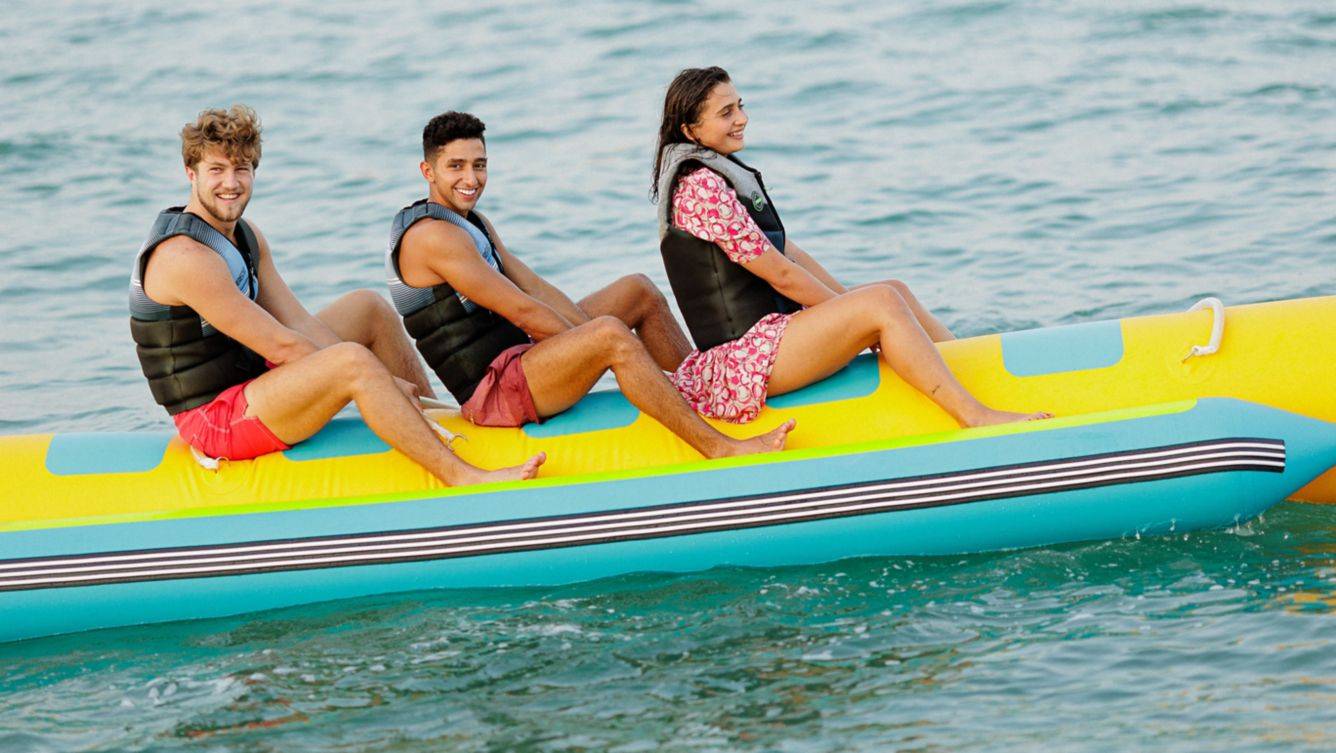 Drei Leute auf einem aufblasbaren Boot im Wasser, alle tragen Schwimmwesten.