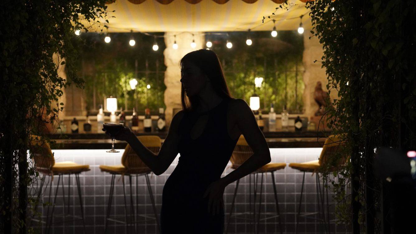 Frau im St. Regis Doha bei der Bar mit einem Glas in der Hand
