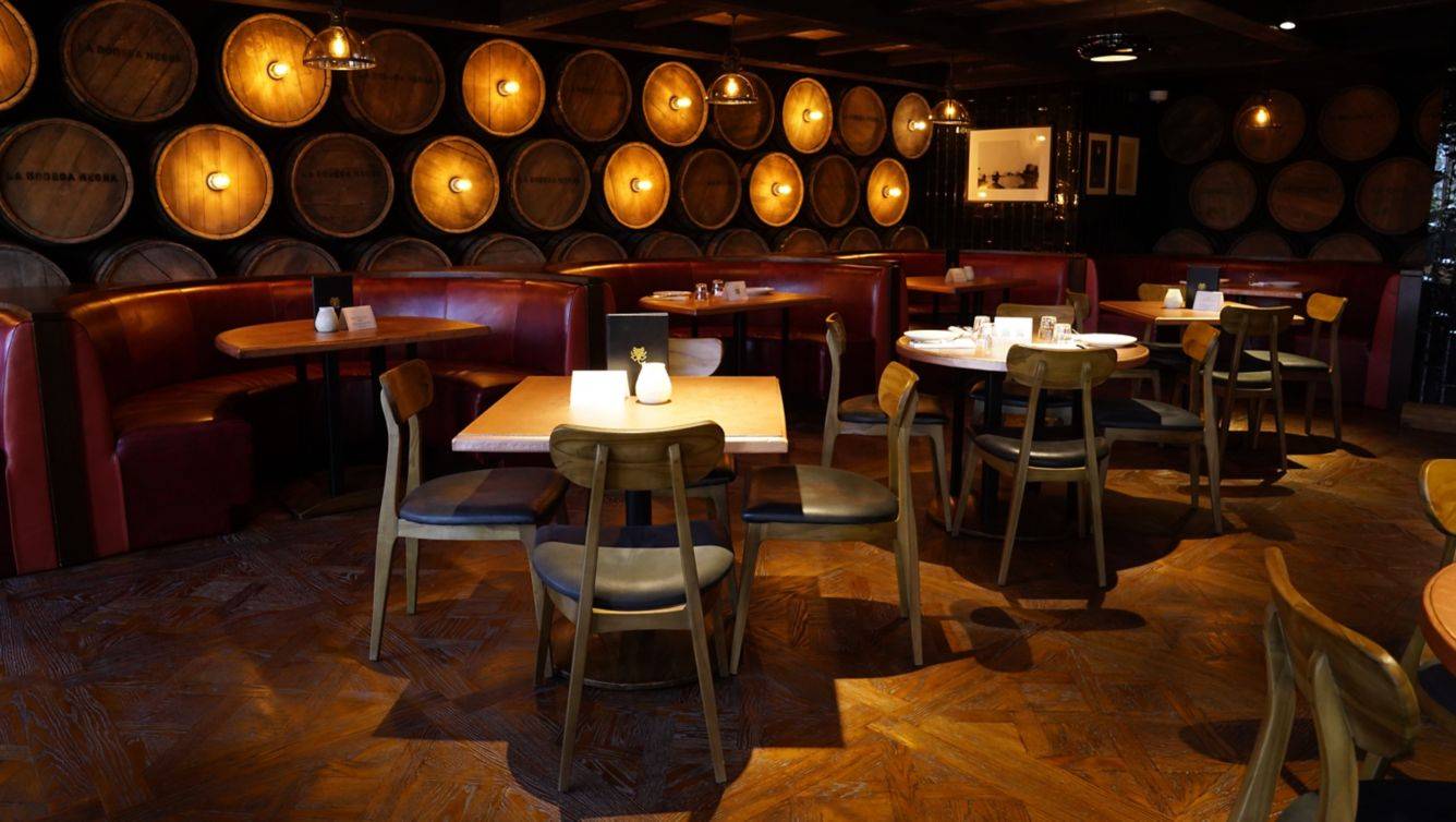 Innenraum des St. Regis Doha Hotel Restaurants mit gepolsterten roten Bänken und Holztischen.