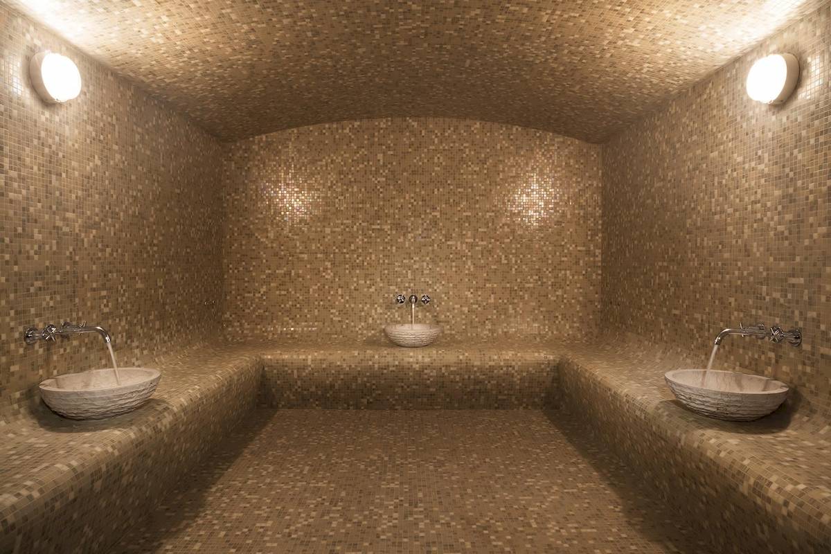 Innenansicht der Sauna im Souq Al Wakra Hotel Qatar By Tivoli mit drei Becken und beige gefliesten Wänden.