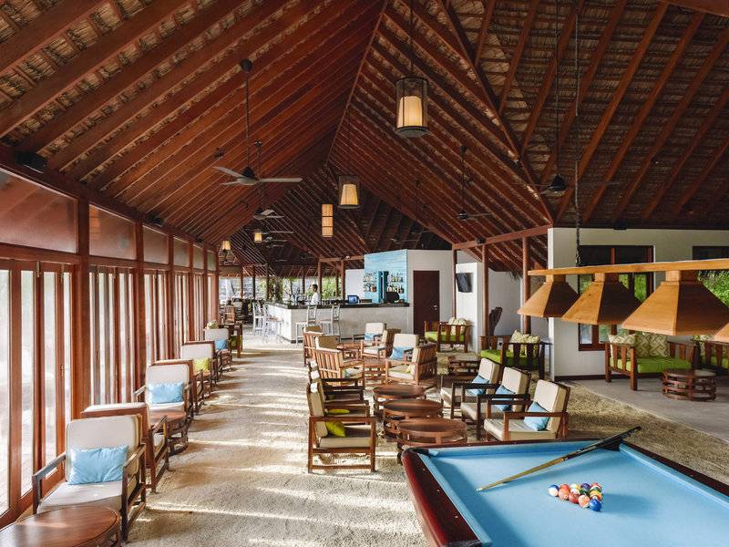 Hotellounge des Summer Island Maldives mit Billardtisch, Holzmöbeln und einer Bar.