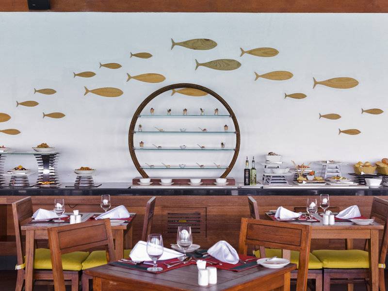 Innenansicht des Restaurants im Summer Island Maldives Hotel mit hölzernen Fischen an der Wand.