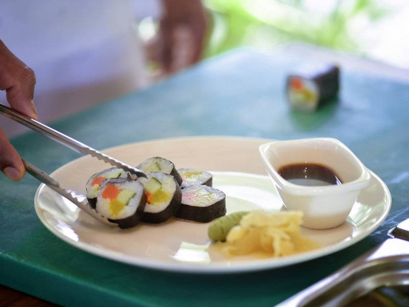 Eine Platte mit verschiedenen Sushi-Rollen und Sojasauce auf einem grünen Tisch.