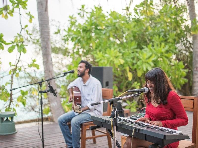 Ein Mann und eine Frau spielen Musik auf der Terrasse des Summer Island Maldives Hotels.