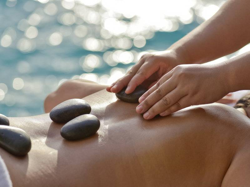 Massage am Strand im Summer Island Maldives mit Steinen auf dem Rücken