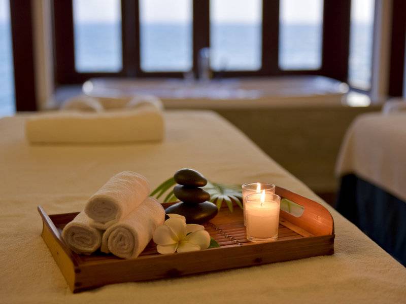 Massagetisch im Summer Island Maldives Hotel mit Kerzen, Blumen und Handtüchern