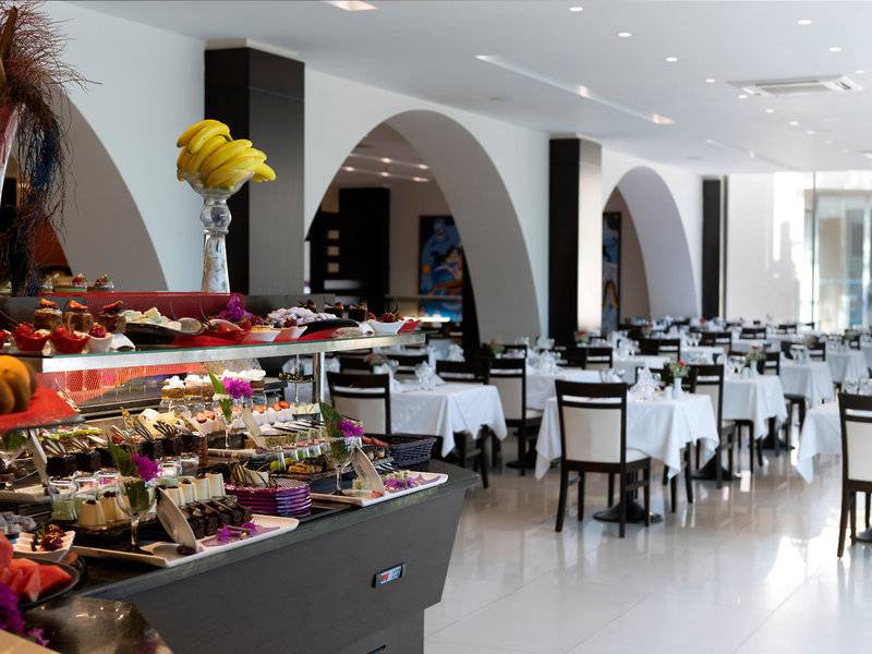Innenansicht des Restaurants im Turquoise Hotel mit Dessertbuffet und gedeckten Tischen.