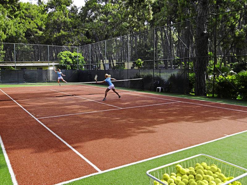 Zwei Spieler spielen Tennis auf einem roten Tennisplatz im Turquoise Hotel.