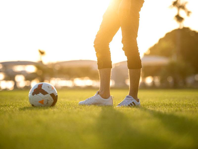 Mann mit Fußball im Stadion, bei Sonnenuntergang