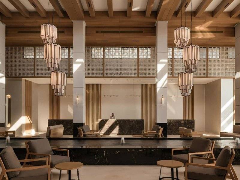 Lobby des JAZ Riviera Hotels mit Empfangstresen, Holzdecken, Marmorboden und modernen Möbeln.