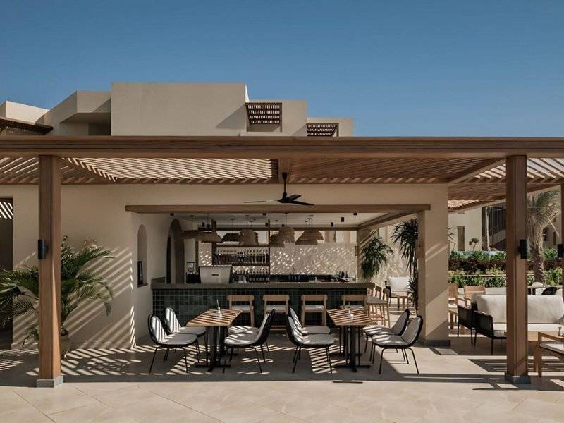 Terrasse im Jaz Riviera Hotel mit Bar, Tischen und Stühlen unter einem Dach.