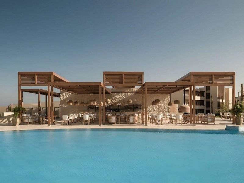 Pool-Lounge-Bereich im JAZ Riviera Hotel mit braunen Überdachungen und weißen Stühlen.