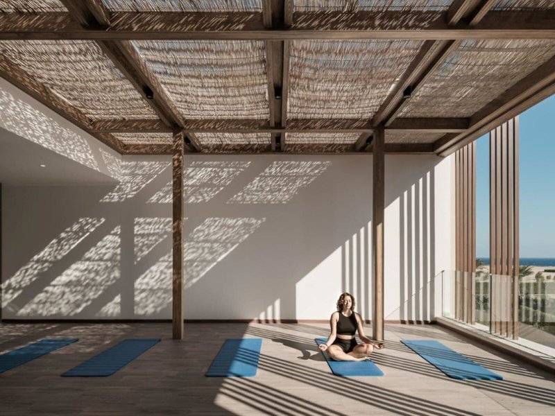 Frau im JAZ Riviera Yoga Studio beim Yoga auf Matte vor Fenstern