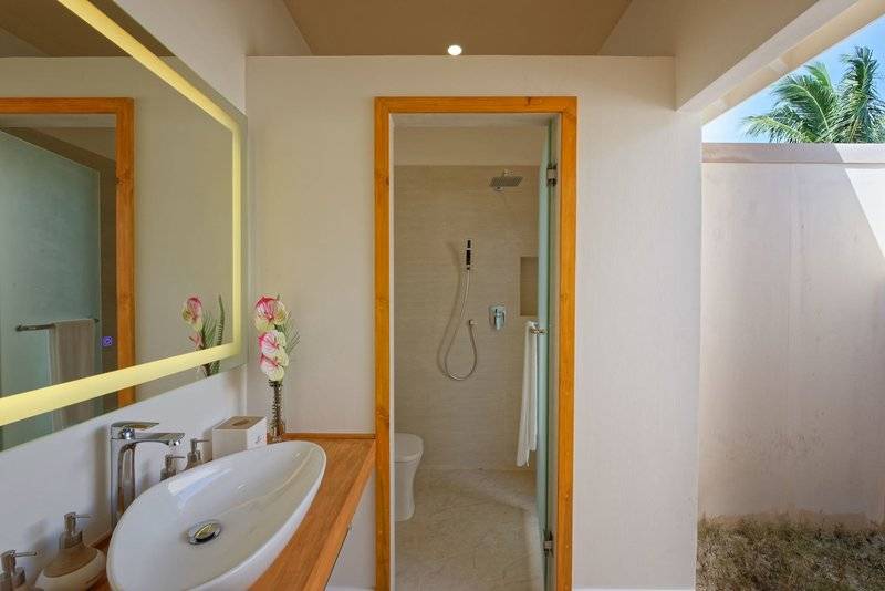 Badezimmer im Brennia Kottefaru Maldives Hotel mit großer Schüssel, Waschbecken und Dusche.
