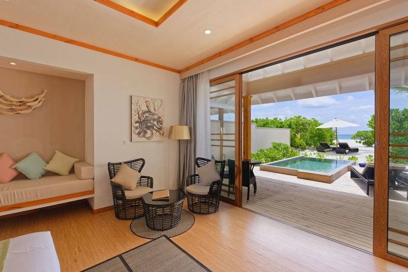 Innenansicht eines Zimmers im Brennia Kottefaru Maldives Hotel mit Blick auf den Pool.