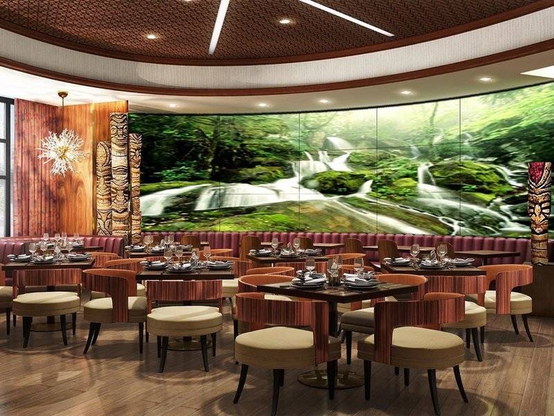 Innenansicht des Restaurants im Hilton Dubai Palm Jumeirah mit grünem Wasserfall-Wandbild.