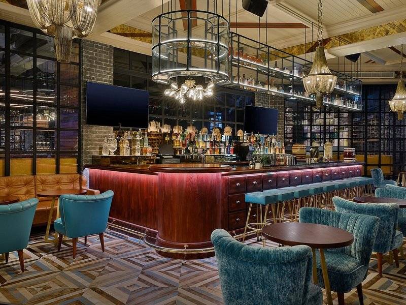 Innenansicht der Bar im Hilton Dubai Palm Jumeirah mit Holztheke und blauen Stühlen.