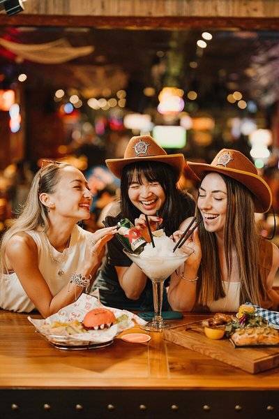 Gruppe von Frauen, die in der Innenbar des Hilton Dubai Palm Jumeirah Cocktails trinken.